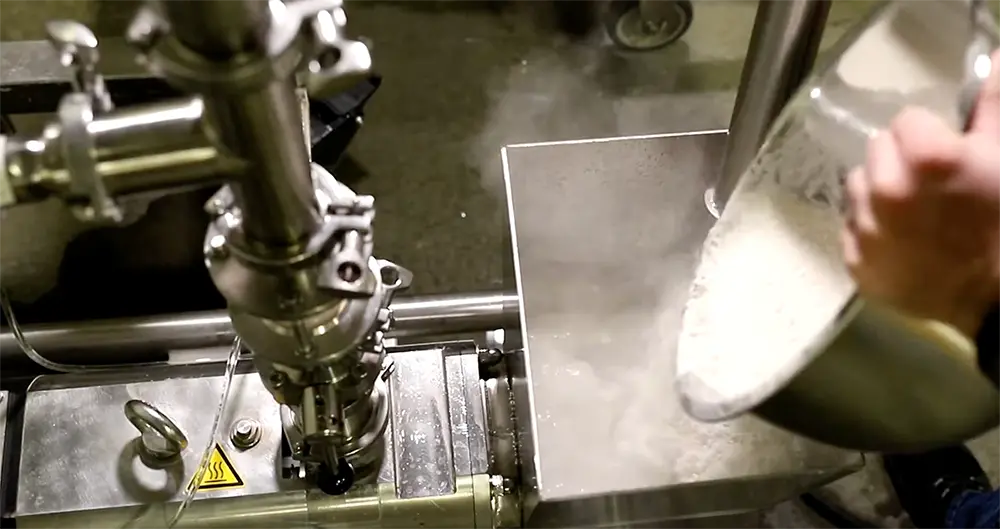A worker pouring fluid into a screw pump assembly